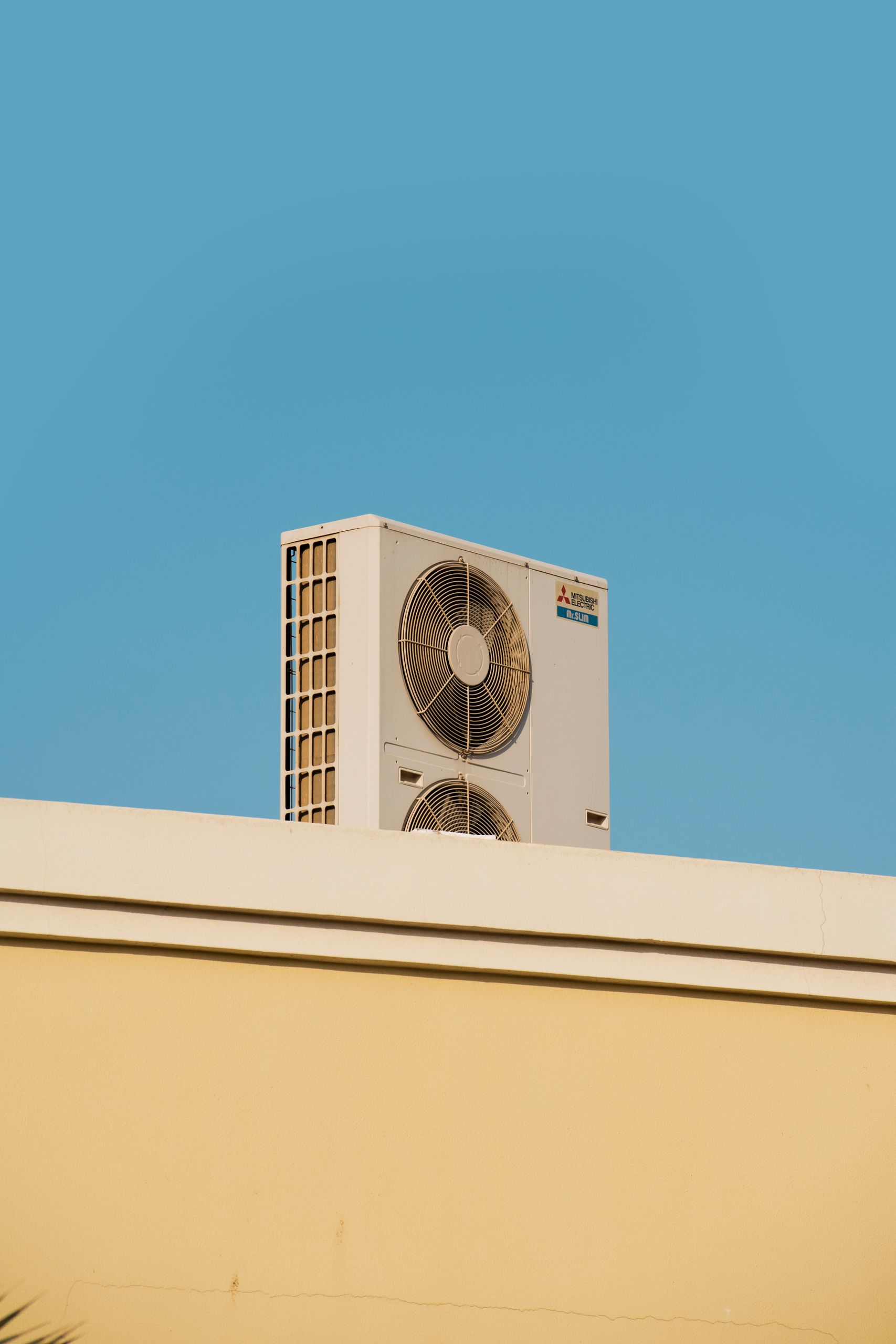 A simple and modern air conditioner unit on a rooftop with a blue sky backdrop in Dubai.