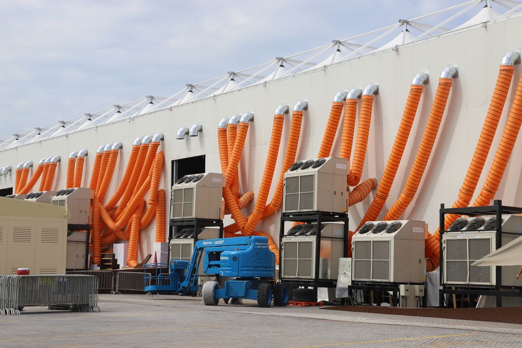 Modern industrial cooling units with striking orange ducts outside a building.