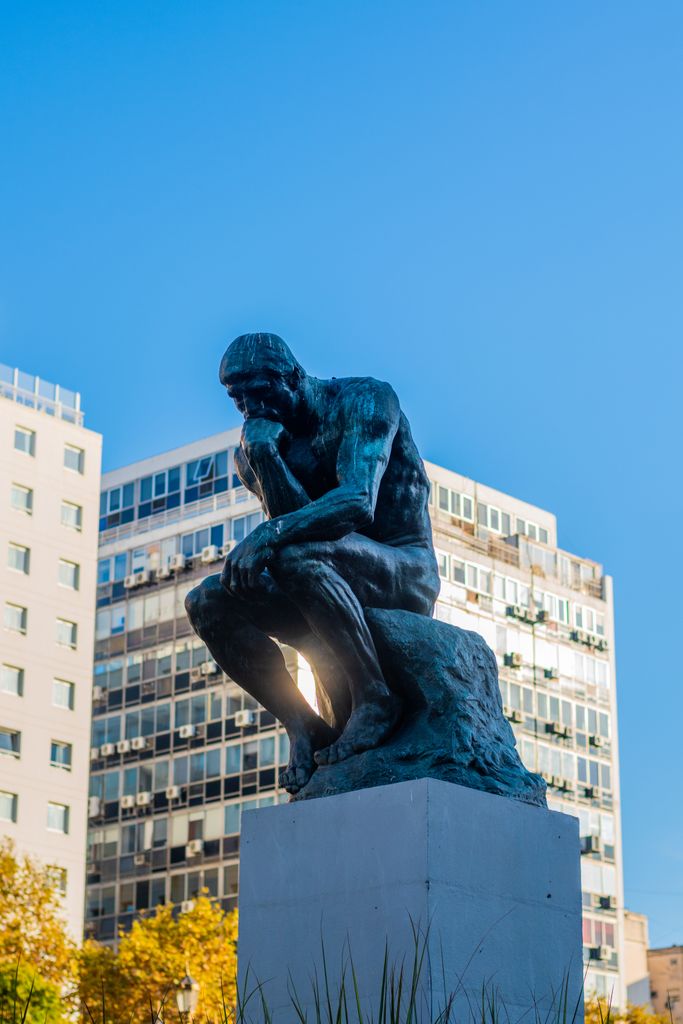 The iconic Thinker sculpture against Buenos Aires skyline, capturing a blend of art and architecture.